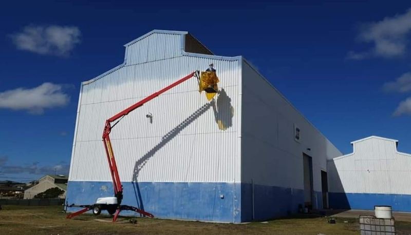Cherry picker reaching the top of an industrial building for cladding work